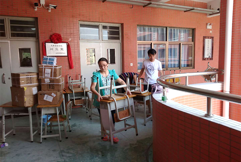 华体会体育志愿者及家长用消毒液擦拭桌椅